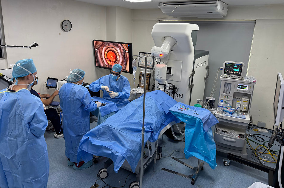 attendees wearing blue in operating room. Image of retina is displayed on the monitor